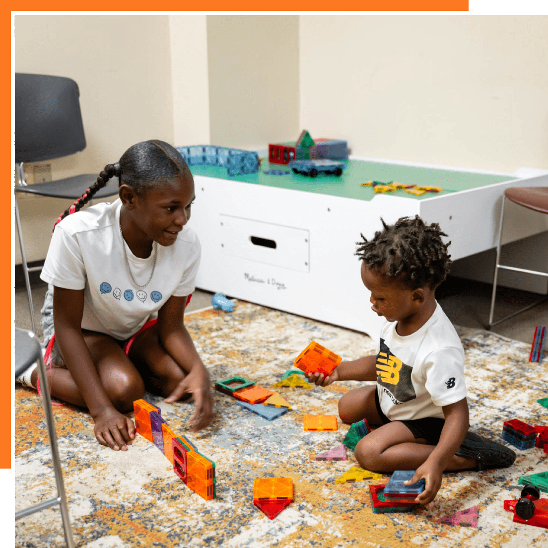 Two children playing with blocks on a carpet in a classroom.